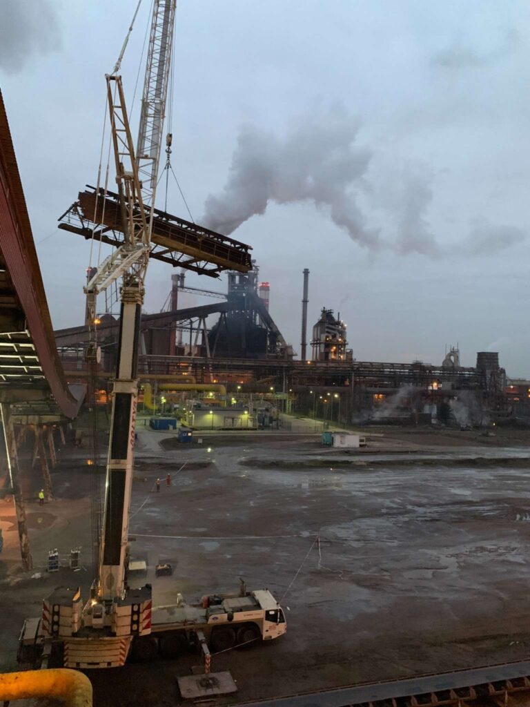 Żuraw samojezdny Demag AC 350 SSL podnosi ciężki, metalowy element podczas demontażu w elektrowni.